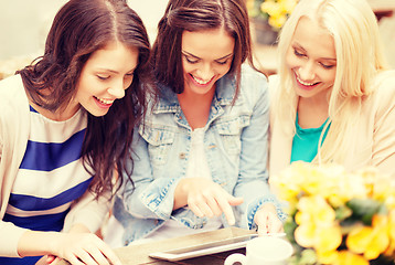 Image showing three beautiful girls looking at tablet pc in cafe