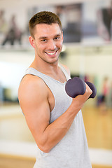 Image showing smiling man with dumbbell in gym