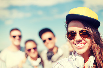 Image showing teenage girl with headphones and friends outside