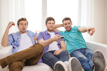 Image showing smiling friends with remote control at home