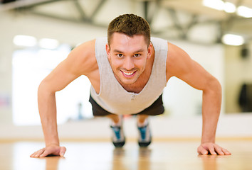 Image showing smiling man doing push-ups in the gym