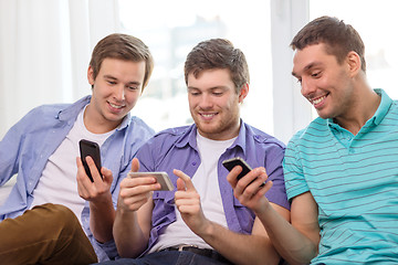 Image showing smiling friends with smartphones at home