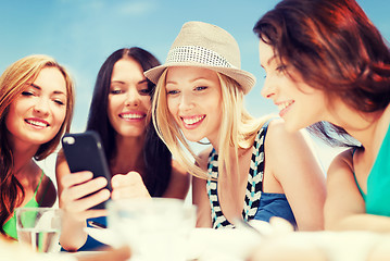 Image showing girls looking at smartphone in cafe on the beach