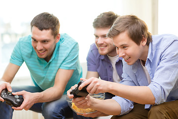 Image showing smiling friends playing video games at home