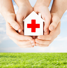 Image showing hands holding paper house with red cross