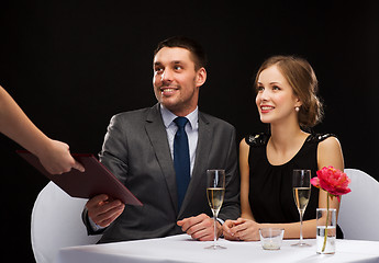 Image showing waiter giving menu to happy couple at restaurant