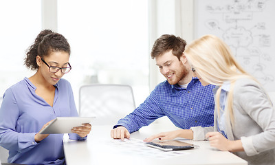 Image showing smiling team with table pc and papers working