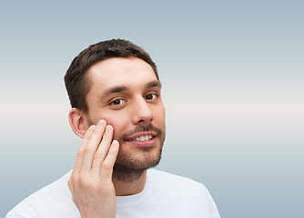 Image showing beautiful smiling man touching his face