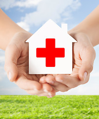 Image showing hands holding paper house with red cross