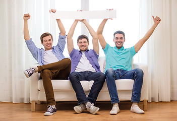 Image showing smiling male friends holding white blank banner