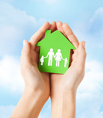 Image showing hands holding green house with family