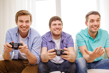 Image showing smiling friends playing video games at home