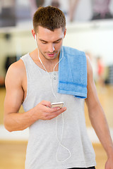 Image showing young man with smartphone and towel in gym