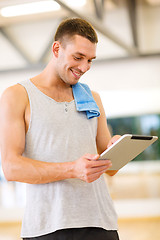 Image showing young man with tablet pc computer and towel in gym