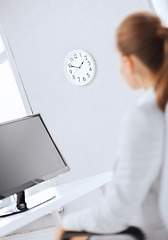 Image showing businesswoman looking at wall clock in office