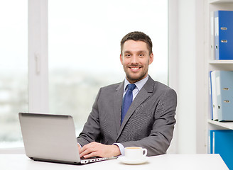 Image showing smiling businessman with laptop and coffee