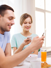 Image showing smiling couple with smartphones reading news