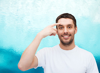 Image showing smiling young handsome man pointing to forehead