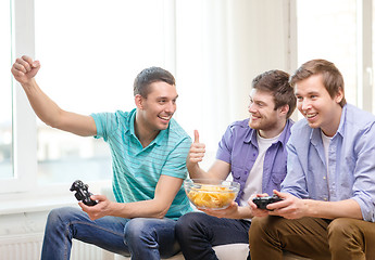 Image showing smiling friends playing video games at home