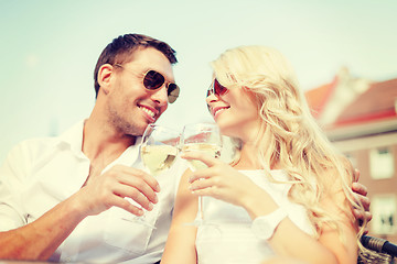 Image showing smiling couple in sunglasses drinking wine in cafe