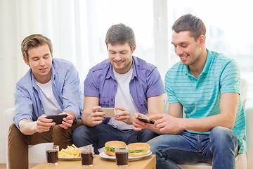 Image showing smiling friends taking picture of food at home