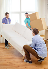 Image showing smiling friends with sofa and boxes at new home