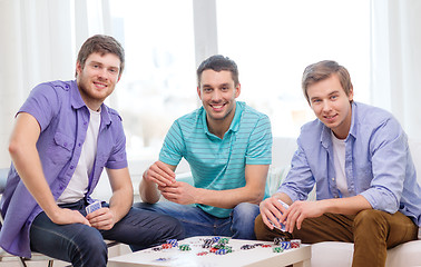 Image showing happy three male friends playing poker at home