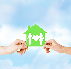 Image showing hands holding green house with family