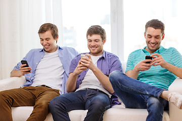 Image showing smiling friends with smartphones at home