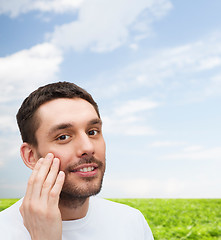 Image showing beautiful smiling man touching his face