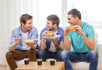 Image showing smiling friends with soda and hamburgers at home