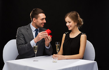 Image showing excited young woman looking at boyfriend with box