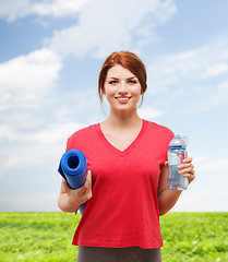 Image showing smiling girl with bottle of water after exercising