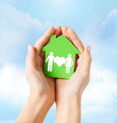 Image showing hands holding green house with family