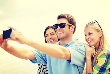 Image showing group of friends taking picture with smartphone