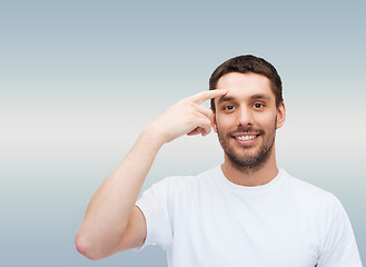 Image showing smiling young handsome man pointing to forehead