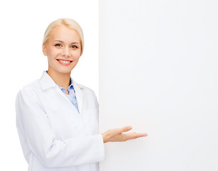 Image showing smiling female doctor with white blank board