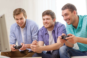 Image showing smiling friends playing video games at home