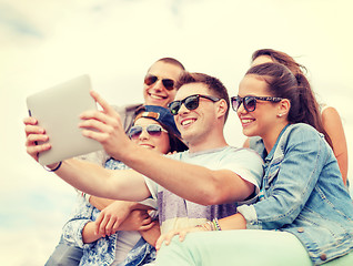 Image showing group of smiling teenagers looking at tablet pc