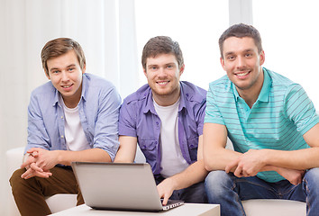 Image showing smiling friends with laptop computer at home