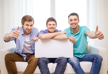 Image showing smiling male friends holding white blank board