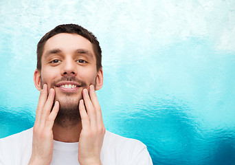 Image showing beautiful smiling man touching his face