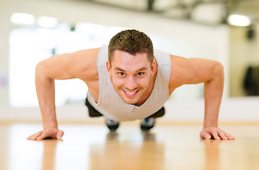 Image showing smiling man doing push-ups in the gym