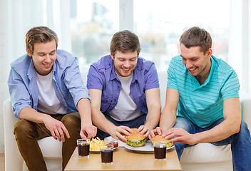 Image showing smiling friends with soda and hamburgers at home