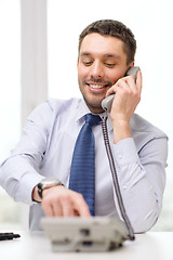 Image showing smiling businessman with telephone dialing number