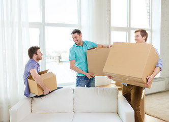 Image showing smiling male friends carrying boxes at new place