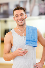 Image showing young man with smartphone and towel in gym