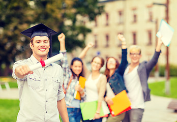 Image showing smiling teenage boy in corner-cap with diploma