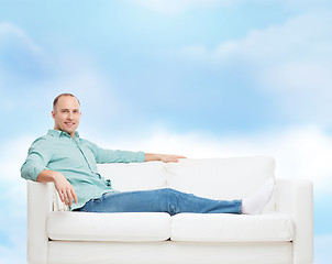 Image showing smiling man lying on sofa