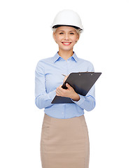 Image showing smiling businesswoman in helmet with clipboard